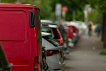 Along a bustling city street, a long row of parked cars, showcasing a variety of automobiles,...