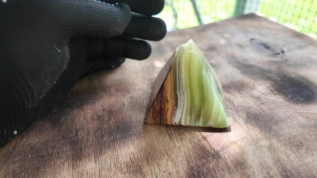 Middle-aged woman with green orgone stone pyramid. triangular stone pyramid. pyramid on the palm. stone symbol. magic item. Man showing a green orgone pyramid, close up