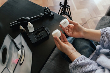 Middle-aged woman beauty blogger filming skincare product unboxing at home with ring light....
