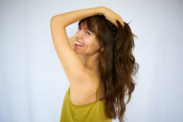 Beautiful happy playful brunette with the big smile holding her beautiful long thick hair on the white background