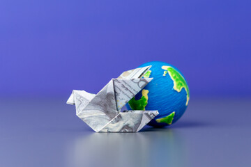An origami bird folded from a US dollar bill and a globe. Global finance, international trade, and...