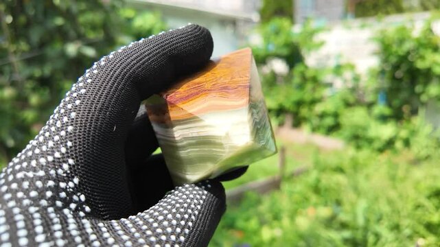 Middle-aged woman with green orgone stone pyramid. triangular stone pyramid. pyramid on the palm. stone symbol. magic item. Man showing a green orgone pyramid, close up