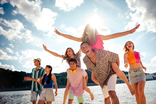 Fellows jumping enjoying a summer day by the water, embracing happiness and friendship outdoors during a sunny vacation