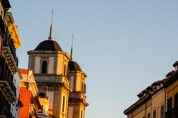 Scenic view of old church towers glowing in golden hour light, surrounded by colorful traditional...