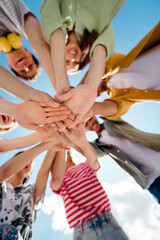 Diverse group of young best friends bonding and stacking hands outdoors on a sunny day, celebrating friendship and togetherness