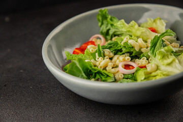 Pasta salad green leaf lettuce, tomato, pasta, onion fresh delicious gourmet food background on the table rustic food top view copy space keto and paleo diet vegan and vegetarian food