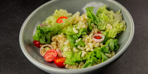 Pasta salad green leaf lettuce, tomato, pasta, onion fresh delicious gourmet food background on the table rustic food top view copy space keto and paleo diet vegan and vegetarian food