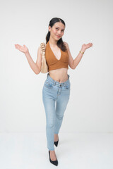Confident young Filipino woman posing with open hands, wearing a brown top and jeans, isolated on a...