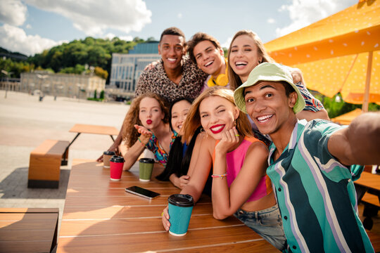 Group of diverse young friends enjoying a summer day outdoors at a cafe, smiling and bonding in a colorful urban setting