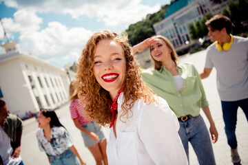 Group of youthful friends enjoying a sunny day outdoors in an urban city environment, displaying...