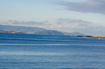 Beautiful tranquil seascape featuring calm blue water, distant coastal mountains, and a peaceful...
