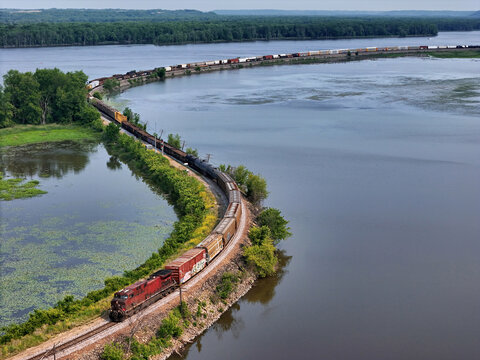 Railroad locomotive pulling a freight train of mixed car types along the Mississippi river