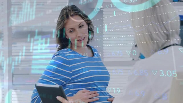 Pregnant patient touching belly and showing tablet while doctor reviewing medical data with charts