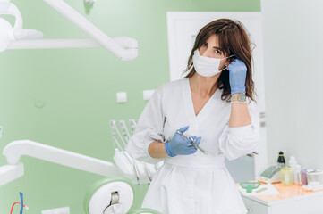Portrait of a young female dentist wearing mask and holding syringe in modern clinic setting