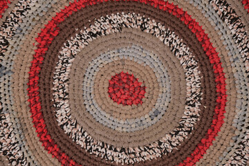 Handmade round wool carpet texture. Ethnic ornament, red-gray-brown tones, handmade, woven rug