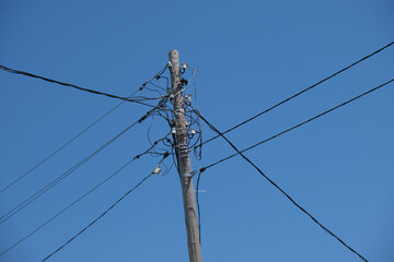Old wooden pole with wires against blue sky. Electricity and infrastructure concept