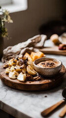 Fototapeta premium Sliced pears and strawberries arranged on a stone board, complemented by a bowl of smooth caramel dip, perfect for a casual breakfast or brunch setting.