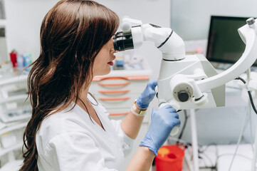 Portrait of a young female dentist working behind modern dental equipment in a clinic.
