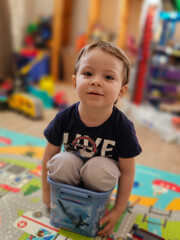 Playful Toddler Sitting in a Toy Bucket