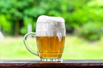 Beer garden, foam pouring from the brewery in a mug, the sun is shining