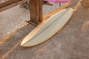 Beige surfboard in the sun. Surfer shortboard on a concrete background in the rays of the setting sun. The concept of sport and surfing on the islands