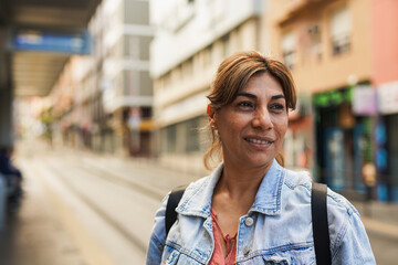 Mature latin woman waiting at tram station in the city - Travel and urban lifestyle concept