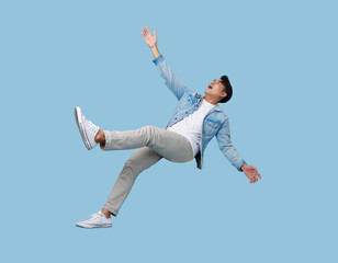 excited asian man relaxing floating in mid-air isolated on blue copy space background.