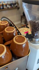 Brown coffee cups on espresso machine with coffee beans in grinder at local coffee shop