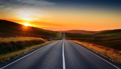 a long straight asphalt road stretches into the horizon disappearing into a beautiful sunset over rolling hills