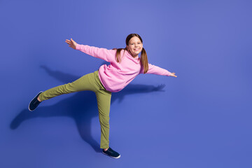 Joyful girl balancing playfully in casual hoodie on colorful background depicting happiness and...