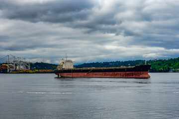 2025-06-0ELLIOTT BAY WITH A LARGE EMPTY CARGO SHIP ANCHORED WITH HARBOR ISLAND IN THE BACKGROUND WITH A CLOUDY SKY