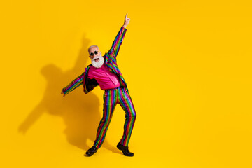 Photo of positive cheerful man wear stylish striped bright outfit suit dance night club party 90s isolated on yellow color background