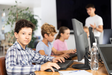 Portrait of male teenage student at computer in school computer class