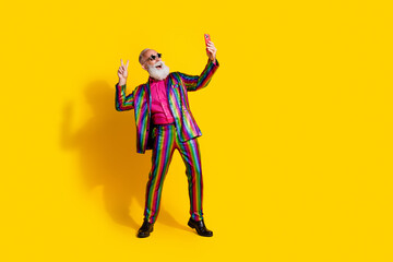 Full body portrait of eccentric man smart phone selfie show v-sign wear shiny costume isolated on yellow color background