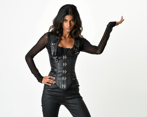Fototapeta premium Close-up portrait of confident brunette woman in black leather corset, posing with confident gesturing hand. steampunk and dystopian style, strong fantasy character, studio portrait with isolated ba