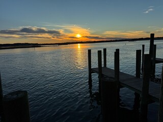 Obraz premium Wooden dock at golden sunset over quiet bay