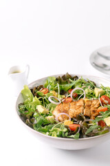 Fresh salad bowl with grilled chicken, avocado, cherry tomatoes, lettuce, and onion rings, served...