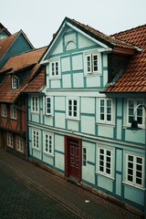 Traditional half-timbered house with red tiled roof and red front door in a historic European old town street.