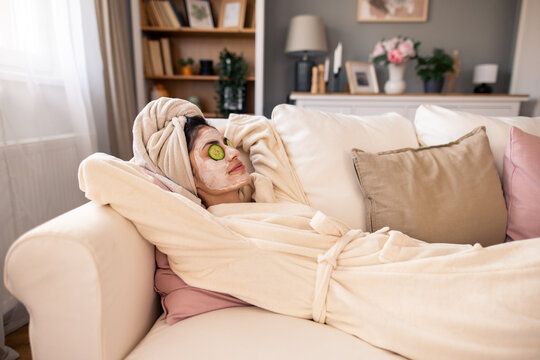 Happy Woman in Beige Robe Relaxing with Face Mask and Towel in Cozy Home Setting - Powered by Adobe