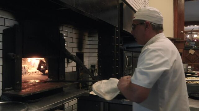 Skilled Chef Tossing Pizza Dough in Air Inside a Professional Kitchen