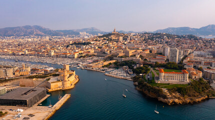 Fototapeta premium Scenic aerial view of coastal area of Marseille overlooking medieval Fort Saint-Jean and Old Port with moored yachts on bank of Gulf of Lion in autumn, France