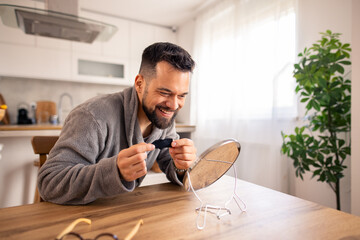 Mid-aged Man With Beard Performing Morning Skincare Routine Using Mirror On Wooden Table In Bright...
