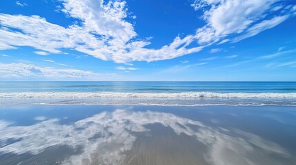 Fototapeta premium Serene Beach Scene with Clear Blue Sky and Gentle Waves Reflecting on Calm Water Surface