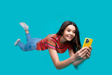Young woman on a dynamic turquoise background enthusiastically using a smartphone, showcasing...