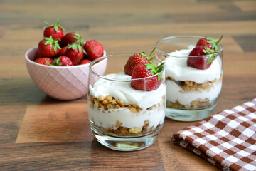 Strawberry Yogurt Parfaits with Granola on wooden background with checkered towel