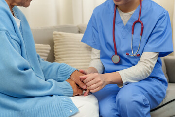 Physiotherapist holds elderly patient’s hands, offering emotional support and encouragement,...