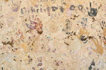 old adobe wall with peeling paint and handprints in different colors