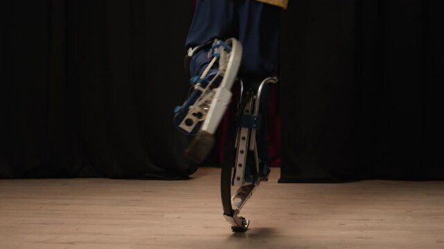 Cropped shot of legs of unrecognizable person bouncing on jumping stilts performing tricks of powerbocking on stage