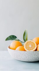 Minimalist still life featuring vibrant oranges in a simple pottery dish. The solid yellow and grey background creates a soft yet dramatic interplay of light and shadow.