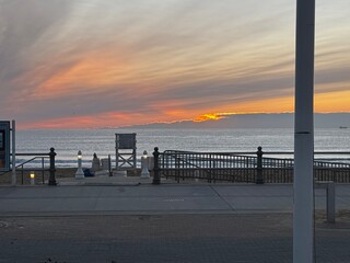 Sunrise peeking over the horizon at Virginia Beach with lifeguard stand and streaked sky